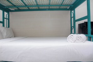 Cozy retreat with a single bed, featuring a neatly rolled towel and a minimalist design.