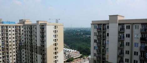 A high-rise residential building with multiple balconies and a view of a residential area in the background.
