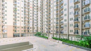 A high-rise residential building with multiple balconies and a parking area. - Comfortable and Tidy 2BR Podomoro Golf View Apartment (Gunung Putri)