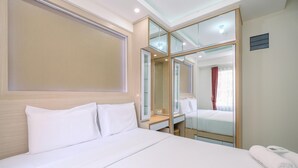 A hotel room with a large bed, a bedside table, a mirror, and a window with curtains. - Comfortable and Tidy 2BR Podomoro Golf View Apartment (Gunung Putri)