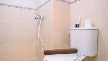 Ein Badezimmer mit Toilette, Dusche und Toilettenpapierhalter.