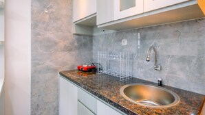 Une cuisine dotée d’un plan de travail en granit, d’un évier en acier inoxydable et de meubles blancs.