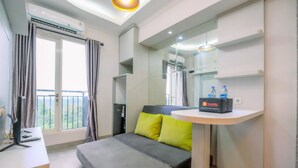 Une chambre d’hôtel moderne équipée d’un lit, d’un bureau avec un ordinateur, d’une petite table avec des bouteilles d’eau et d’un balcon avec des rideaux.