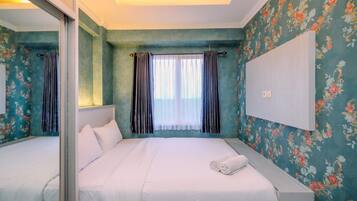 Ein Hotelzimmer mit einem großen Bett, einem Spiegel und blumigem Wandpapier.