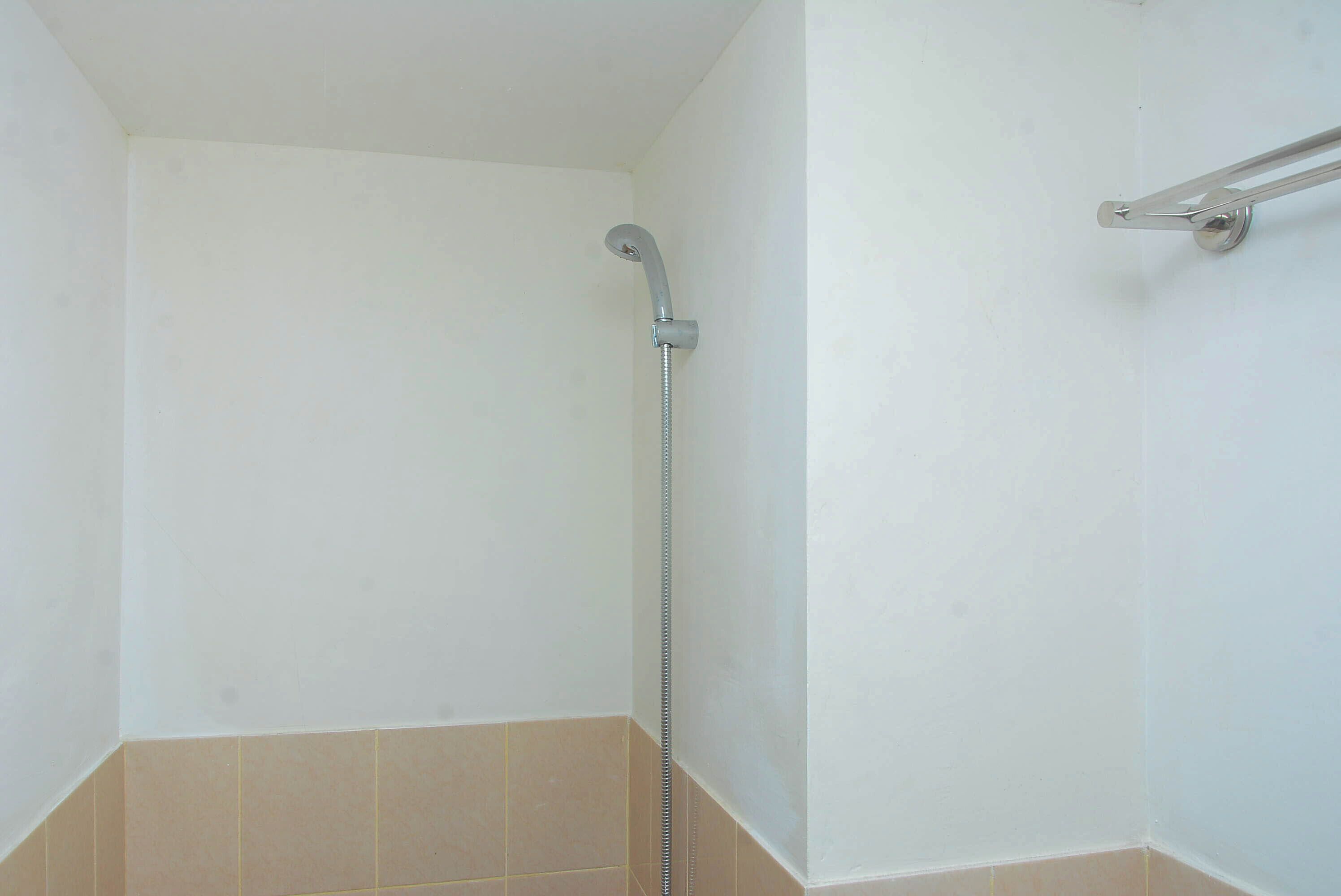 Een kleine badkamer met witte wanden, een douche en een handdoekrek.