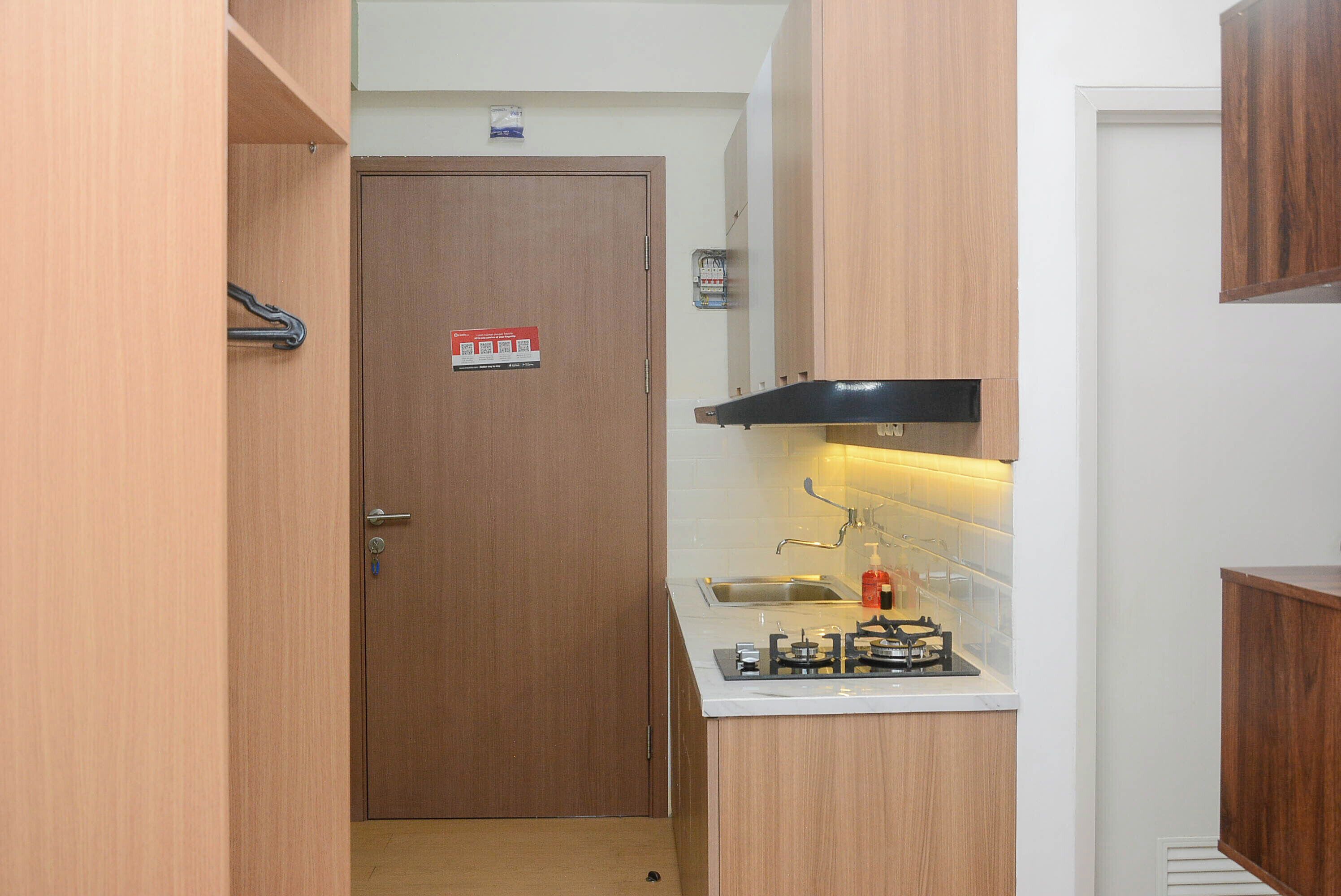 Een compacte keuken met een ingebouwd gasfornuis, een klein spoelgedeelte en houten keukenkastjes.