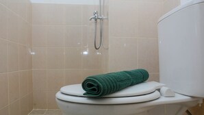 Een badkamer met toilet, douche en beige betegelde wanden.