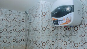 A bathroom with patterned tiles and a wall-mounted shower unit.