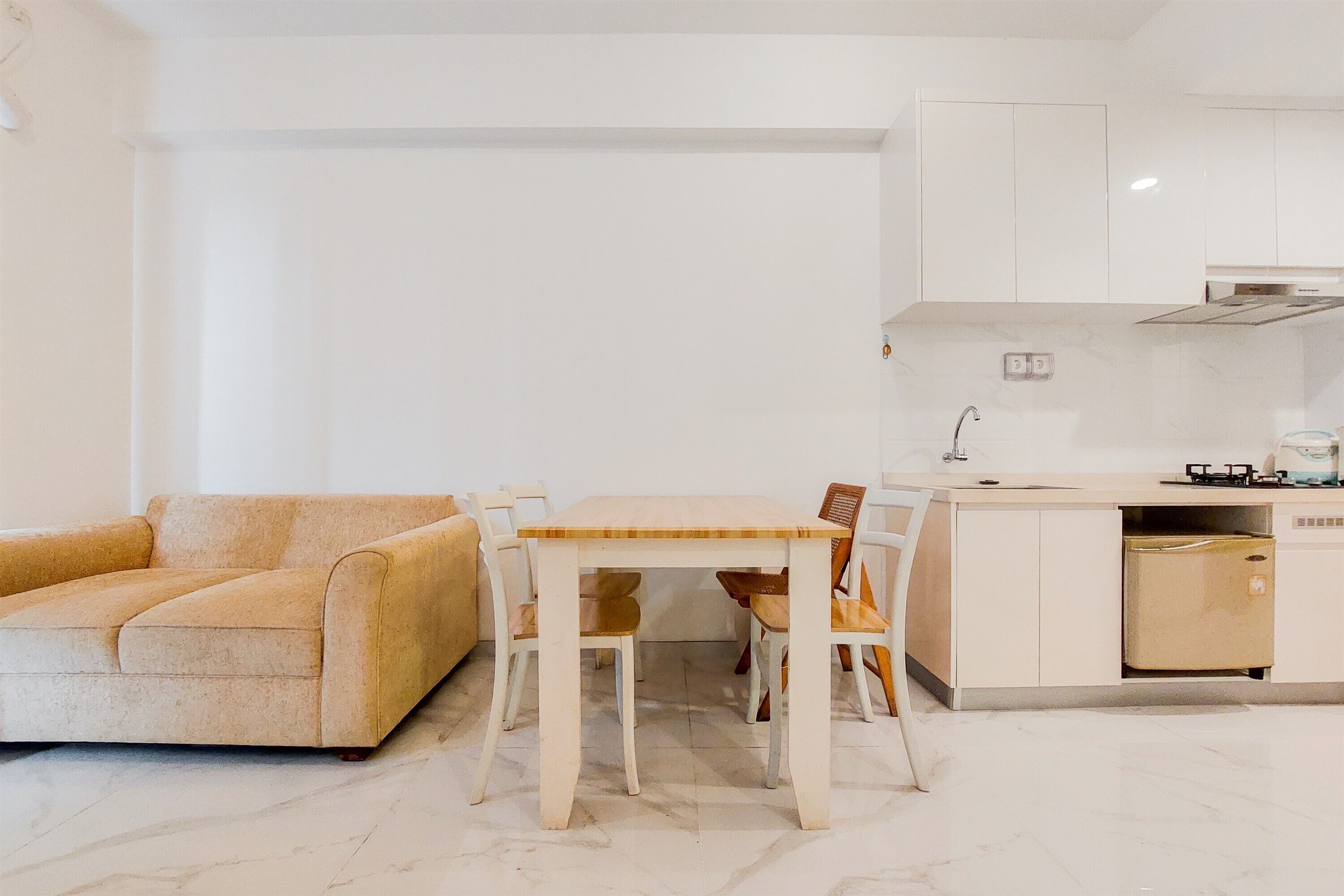 A compact living space with a sofa, a dining table with chairs, a kitchen area with cabinets, and a built-in dishwasher.