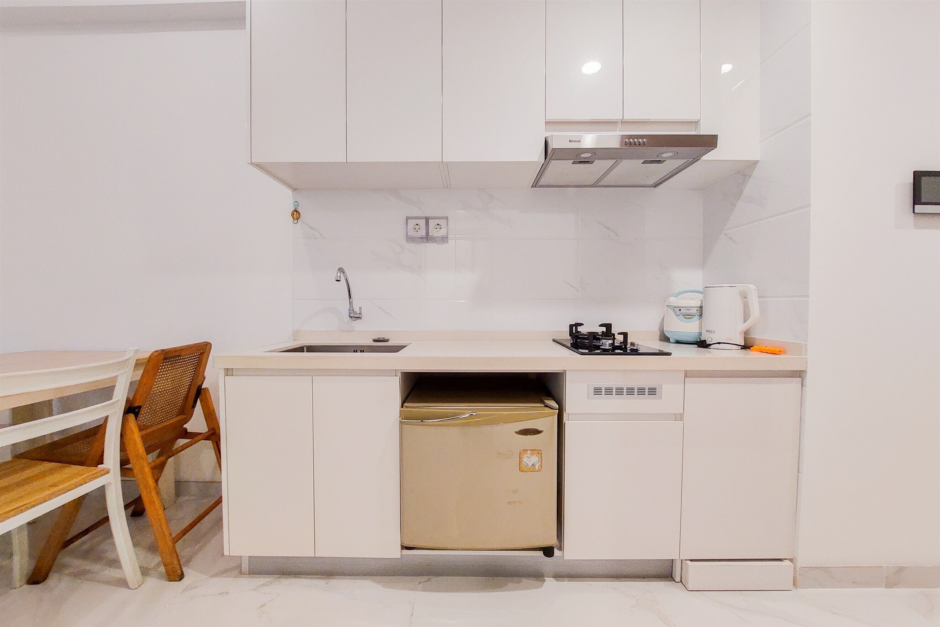 A compact kitchen with white cabinets, a built-in dishwasher, a sink, and a coffee maker.