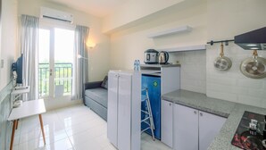 A compact kitchen with a refrigerator, coffee maker, and a blue cabinet. - Fully Furnished with Cozy Design 2BR Podomoro Golf View Apartment (Gunung Putri)