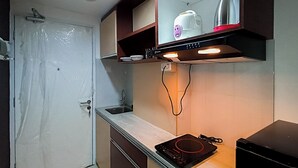 A kitchen with a built-in stove, a sink, and a microwave. - Brand New and Homey Studio at Tamansari Skylounge Makassar Apartment (Makassar)