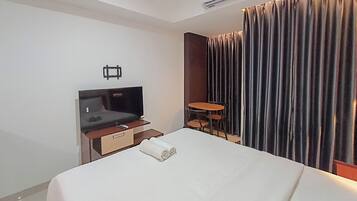 Una habitación de hotel con una cama, televisión, una mesita y una silla.