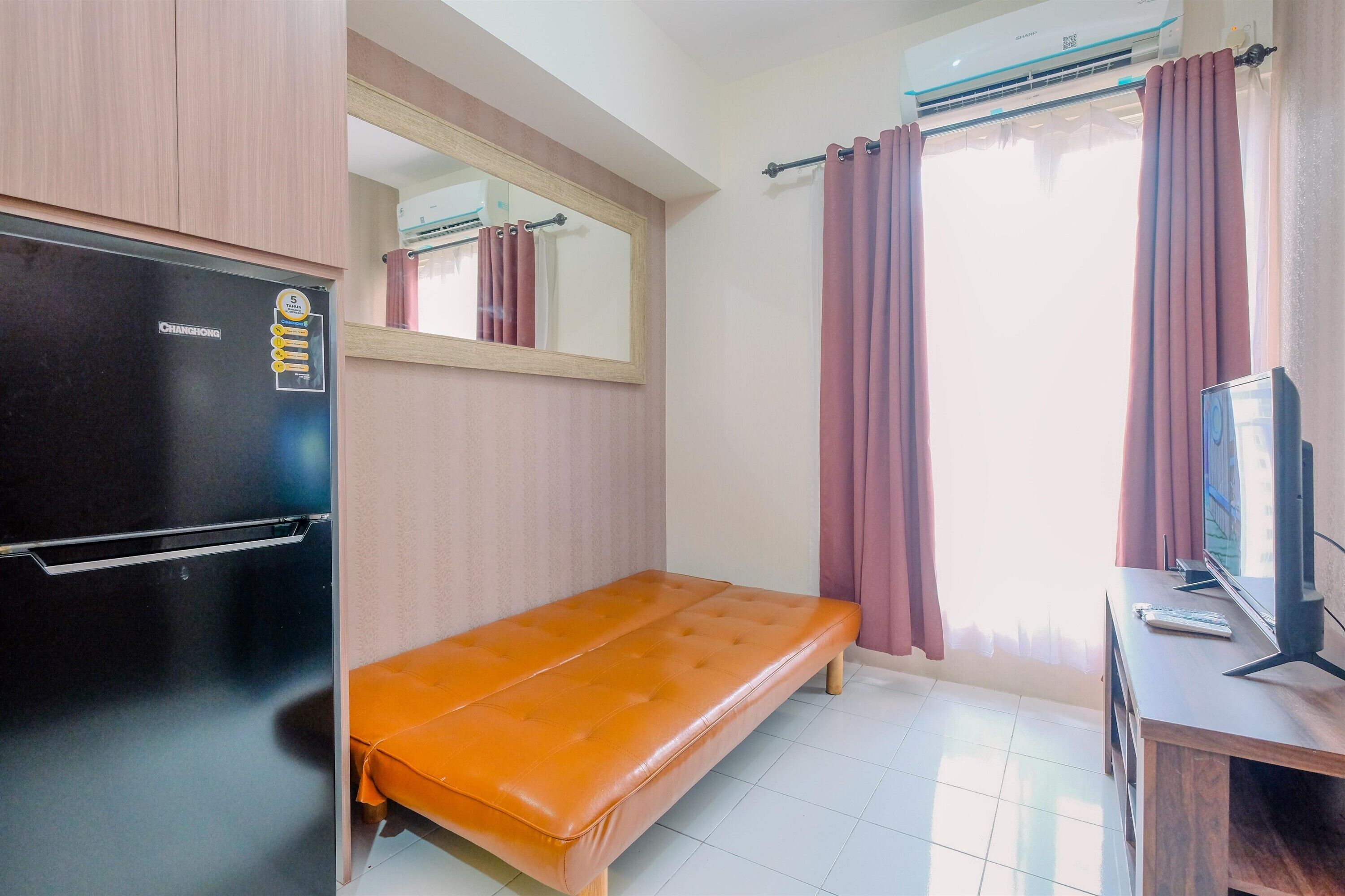 A compact room with a bed, a television, and a refrigerator.