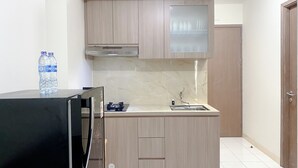 Een kleine keuken met houten kastjes, een roestvrijstalen spoelbak en een ingebouwde kookplaat.