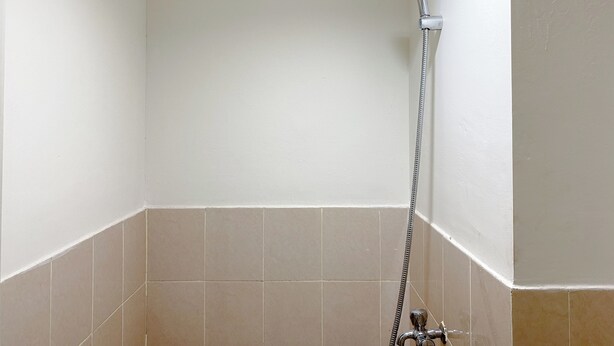 Un baño pequeño y vacío con paredes blancas y baldosas color crema.