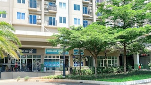 A multi-story building with balconies, a restaurant named "Emaluna La Cantina," and a sign for "Emaluna La Cantina." - Cozy and Simply Look 2BR Podomoro Golf View Apartment (Gunung Putri)