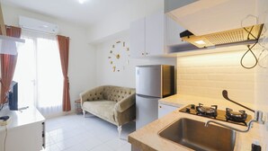 A compact kitchen with a gas stove, a refrigerator, and a sink. - Cozy and Simply Look 2BR Podomoro Golf View Apartment (Gunung Putri)