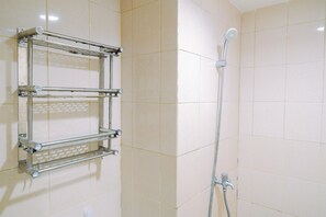 Une salle de bain avec une douche, un porte-serviettes en métal et des murs carrelés.