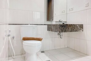 Une salle de bain moderne avec des toilettes blanches, un lavabo en marbre et un espace douche.