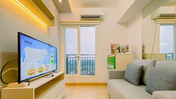 Una sala de estar moderna con una televisión de pantalla plana sobre un mueble bajo, un sofá gris y un balcón con barandilla.