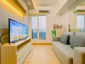 Una sala de estar moderna con una televisión de pantalla plana sobre un mueble bajo, un sofá gris y un balcón con barandilla.