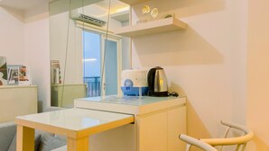 Una habitación moderna con una mesa de vidrio, una tetera, una cafetera, una silla y una ventana con vistas.