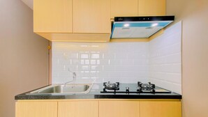 A compact kitchen with a double sink, a gas stove, and a built-in oven. - Good Place 2BR at Podomoro Golf View Apartment (Gunung Putri)