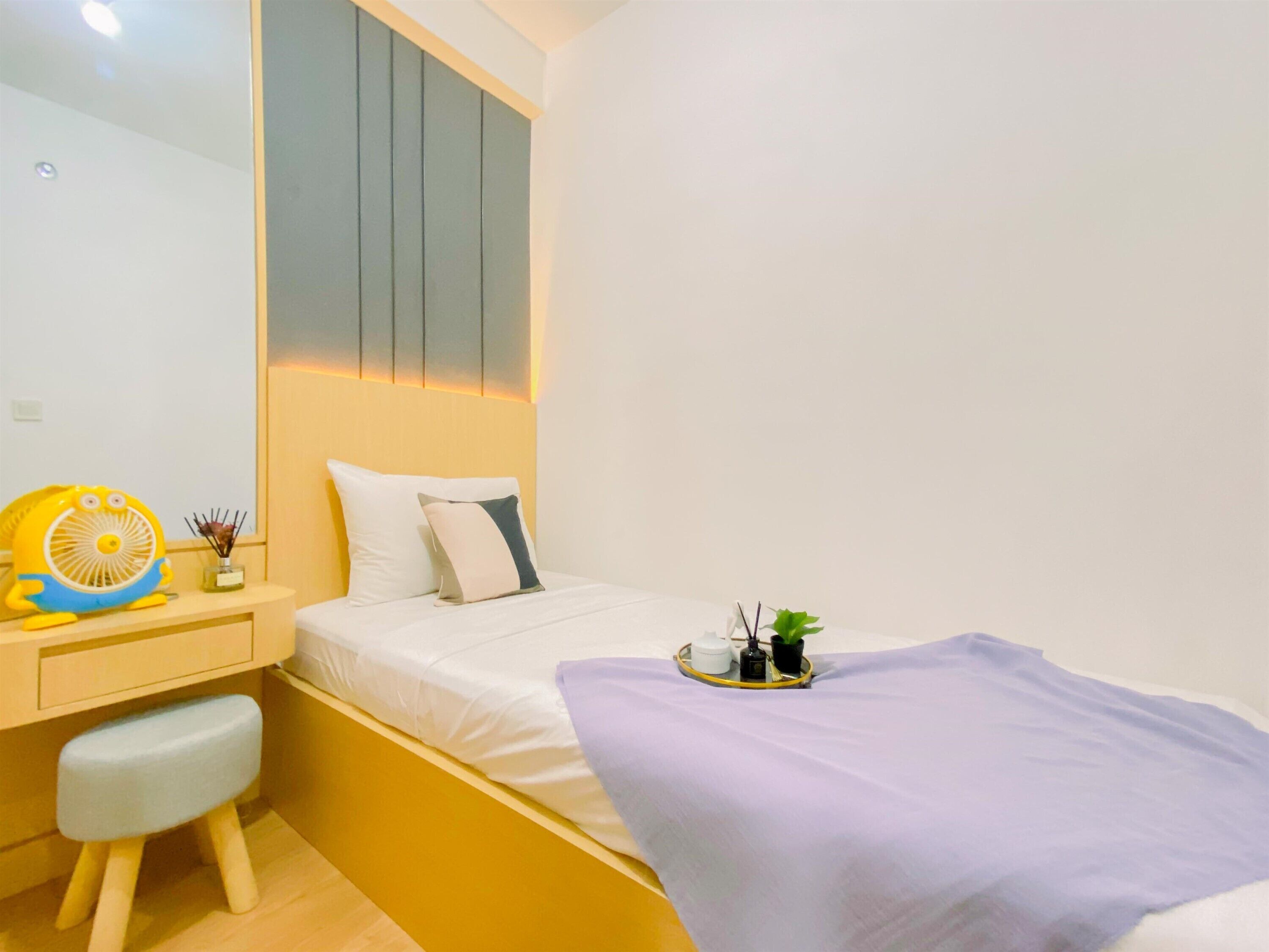Un dormitorio con cama, mesita de noche y un taburete pequeño.