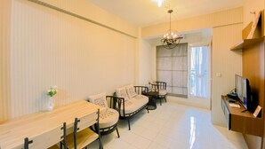A modern living room with a dining area, a sofa set, a chandelier, and a television. - Well Furnished and Comfy 3BR Podomoro Golf View Apartment (Gunung Putri)