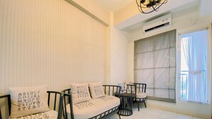 A modern living room with a sofa set and chairs, a small table, and a large window with curtains. - Well Furnished and Comfy 3BR Podomoro Golf View Apartment (Gunung Putri)