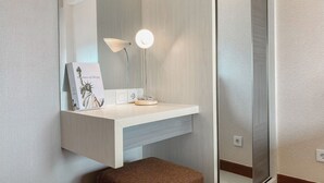 Un baño moderno con un tocador blanco, un espejo, una lámpara y un taburete marrón.