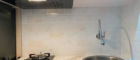 A kitchen with a gas stove, a stainless steel sink, and a modern range hood.