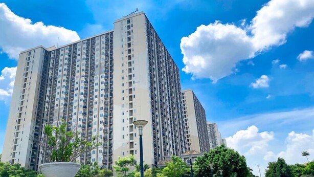 A high-rise residential building with multiple balconies, surrounded by greenery and under a clear sky. - Tranquil and Homey Studio at Podomoro Golf View Apartment (Gunung Putri)