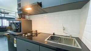 A modern kitchen with a black countertop, stainless steel sink, and a built-in oven. - Tranquil and Homey Studio at Podomoro Golf View Apartment (Gunung Putri)