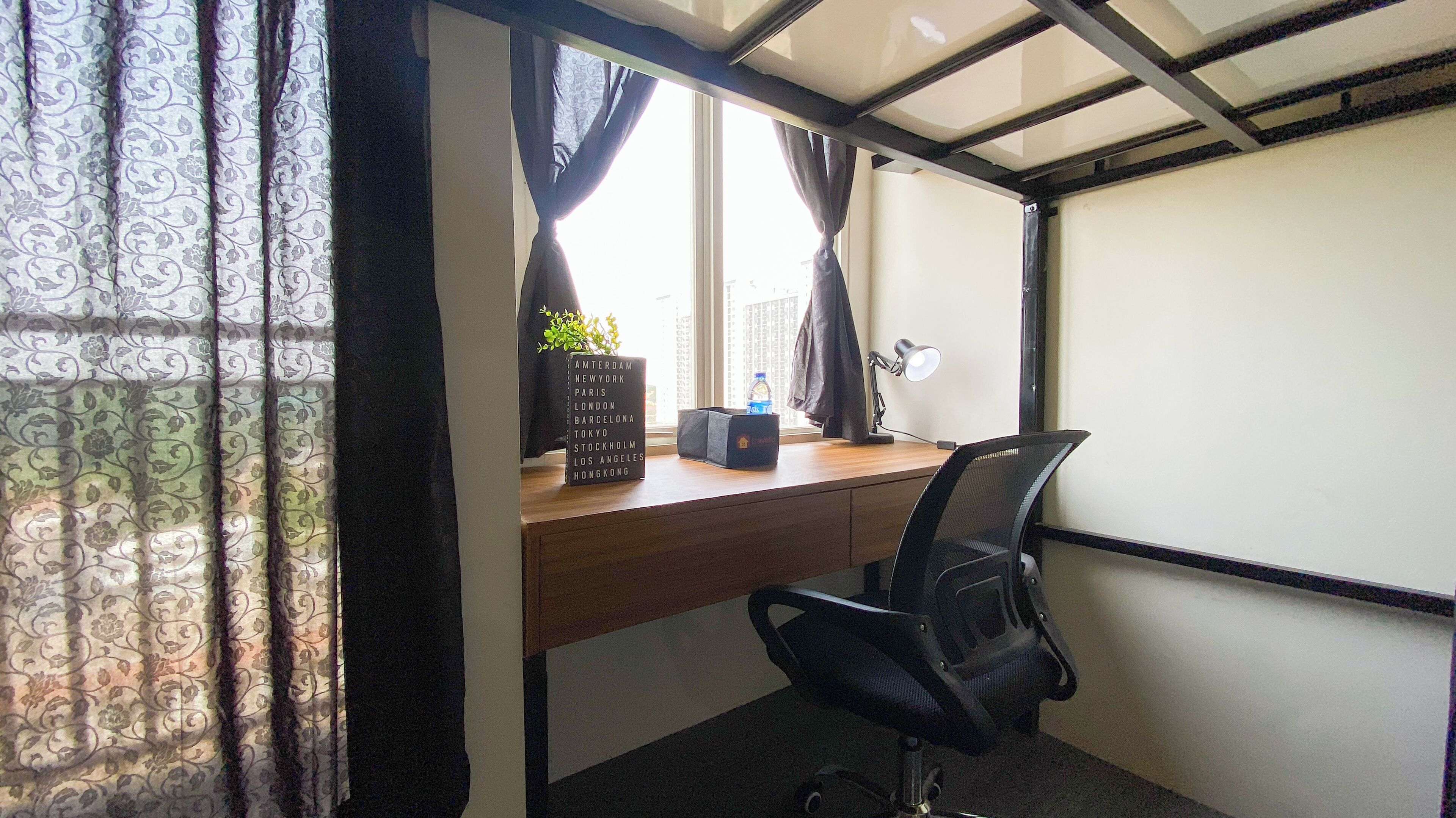 Ein kompakter Arbeitsbereich mit Schreibtisch, Stuhl und einem fenster mit Vorhängen.