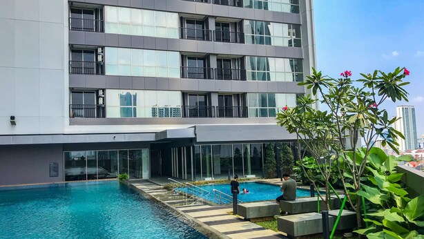 Un hotel moderno con piscina, grandes ventanales y vistas del horizonte urbano.