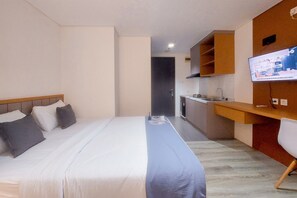 A compact hotel room with a bed, a small kitchenette, and a TV mounted on the wall. - Cozy Studio Apartment at Bintaro Icon (South Tangerang)