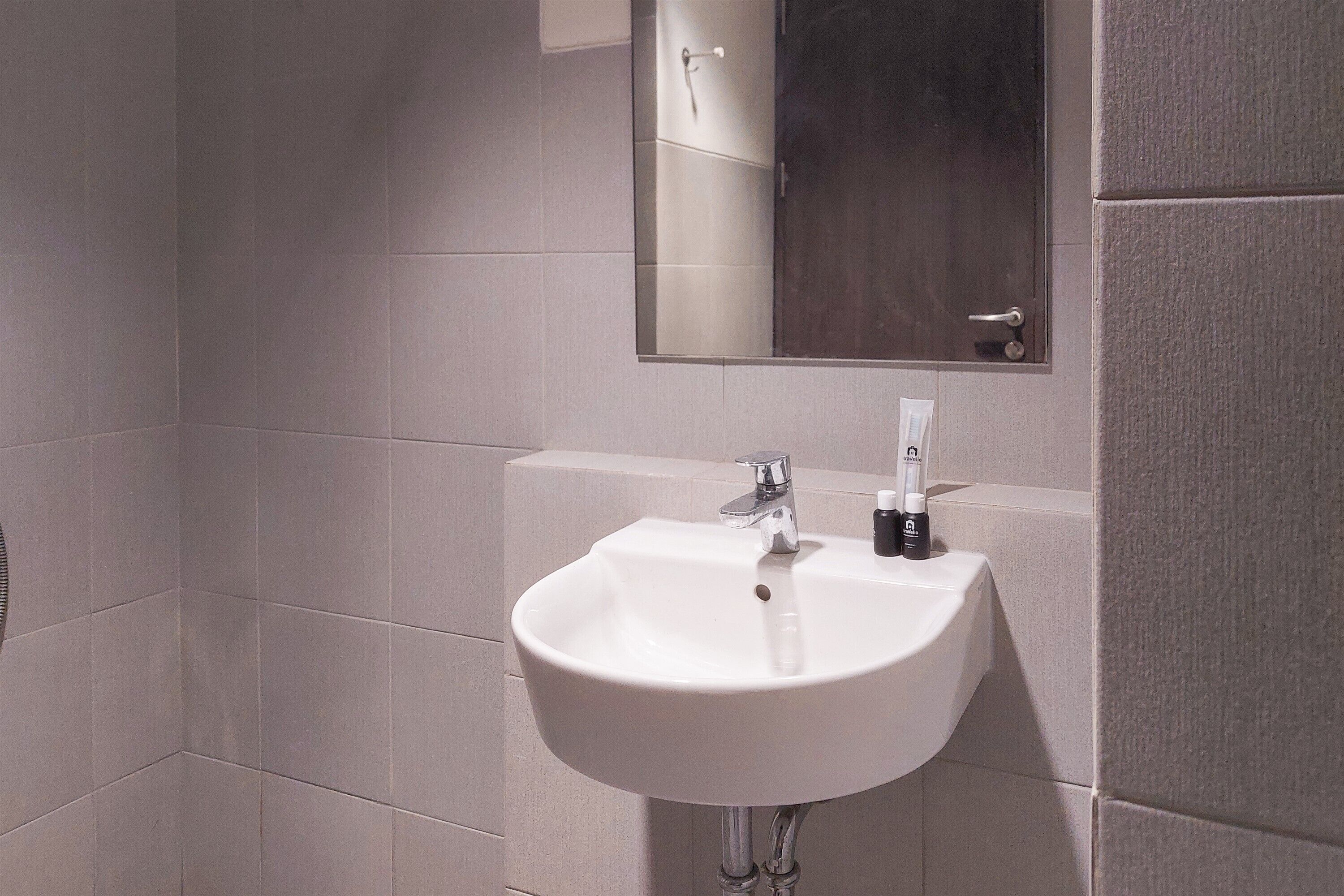 Une salle de bain avec un lavabo blanc, un miroir et un distributeur de serviettes.