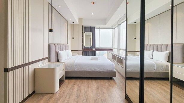 Ein modernes Hotelzimmer mit einem großen Bett, Nachttischen, einem Spiegel und Blick auf die Stadt.