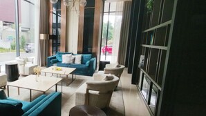 Ein modernes Interieur mit einem blauen Sofa, weißen Sesseln, einem Couchtisch und einem runden Hocker.
