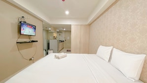 A hotel room with a large bed, a television mounted on the wall, a mirror, and a wardrobe. - Good Homey Studio Apartment at Warhol (W/R) Residences (Semarang)