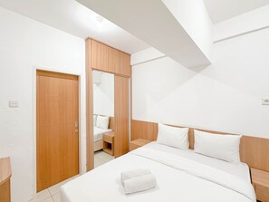 Ein modernes Schlafzimmer mit einem Holzschrank, einem Bett mit weißer Bettwäsche und einem Spiegel.