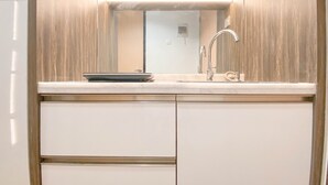 A modern kitchen with a built-in sink, a mirror above it, and a stainless steel faucet. - Cozy and Homey Studio at The Alton Apartment (Semarang)