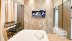 A modern hotel room with a large bed, a mounted TV, and a wardrobe with a mirror. - Cozy and Homey Studio at The Alton Apartment (Semarang)
