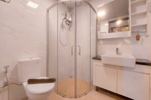 A bathroom with a glass-enclosed shower, a toilet, and a sink with a mirror above it. - Elegant and Comfort 3BR at Sky House BSD Apartment (Pagedangan)