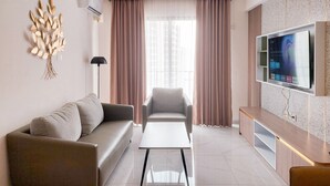 Ein modernes Wohnzimmer mit Sofa, Sessel, Couchtisch und einem an der Wand montierten Flachbildfernseher.