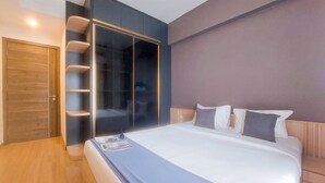 Ein modernes Schlafzimmer mit einem großen Bett, einem Schrank mit Glastüren und Holzdielen.