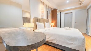 A modern hotel room with a large bed, a bedside table, a lamp, and a mirror. - Wonderful 2BR with City View at Grand Sungkono Lagoon Apartment (Surabaya)