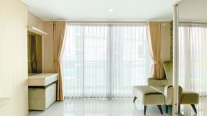 A spacious room with a large window, a seating area with a chair, and a small table.